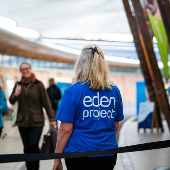 Eden Project staff member with back to the camera welcoming guests